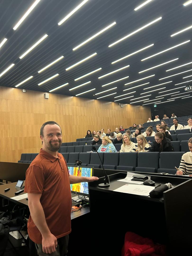 Rex står framför publiken i föreläsningssalen